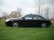 2000 Ford Taurus - A black sedan is parked on a grassy area with trees in the background under an overcast sky.