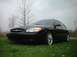 2000 Ford Taurus - A black 2000 Ford Taurus sedan with custom chrome wheels is shown from a low angle in a grassy area.