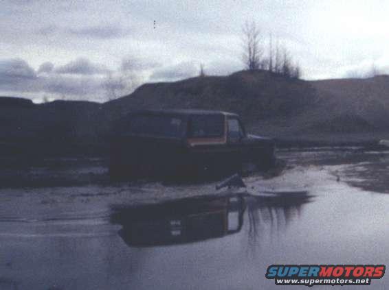 1978 Ford Bronco stuck in mud with reflection