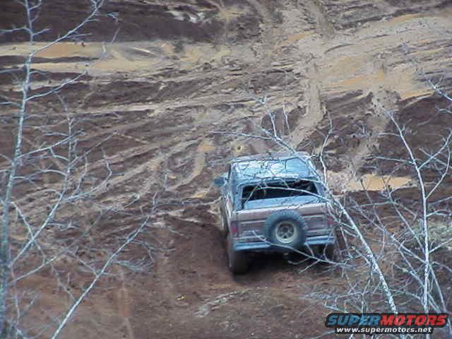 1978 Ford Bronco driving up a muddy hill, spare tire mounted on rear door