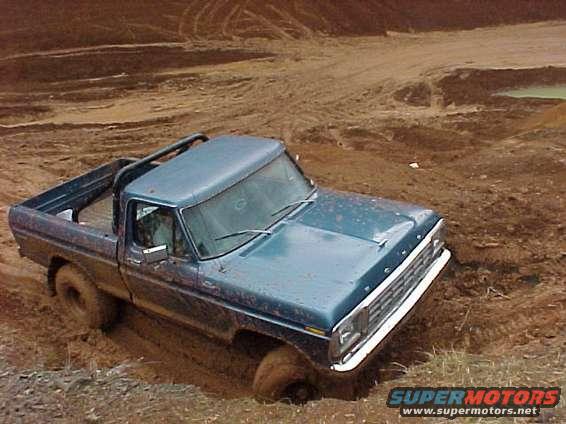 Blue pickup truck stuck in mud, front end visible