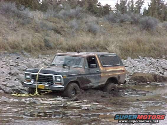 1978 Ford Bronco stuck in mud with a tow strap attached to the front