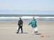 1996 Ford Bronco - Two individuals participate in a beach cleanup, collecting debris along the shore under a bright sky.