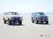 1996 Ford Bronco - Two Ford Broncos are parked on a beach, with the ocean visible behind them.