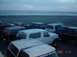 1996 Ford Bronco - Several Ford Bronco SUVs are parked on a beach near the ocean.