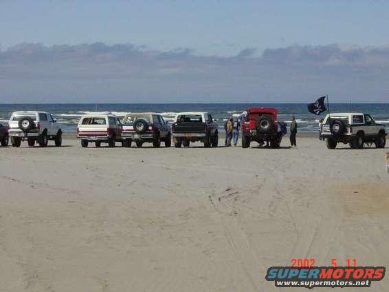 White Ford Bronco with spare tire on rear, parked on sandy beach