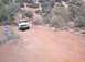 1979 Ford Bronco - A white Ford Bronco navigates a dusty, off-road trail with desert scrub brush.
