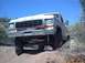 1979 Ford Bronco - Ford F-Series truck navigating an off-road incline under a clear blue sky.