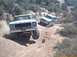 1979 Ford Bronco - Two trucks navigate a dusty, off-road trail with steep inclines and sparse vegetation.