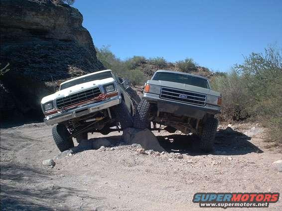 White 1979 Ford Bronco and silver Ford truck on rocky terrain
