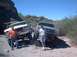 1979 Ford Bronco - Two Ford trucks are parked on a rocky, off-road trail in a desert landscape.