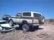 1979 Ford Bronco - A two-tone brown and white 1978 Ford Bronco is parked on a rocky incline, with another vehicle partially visible in the background.