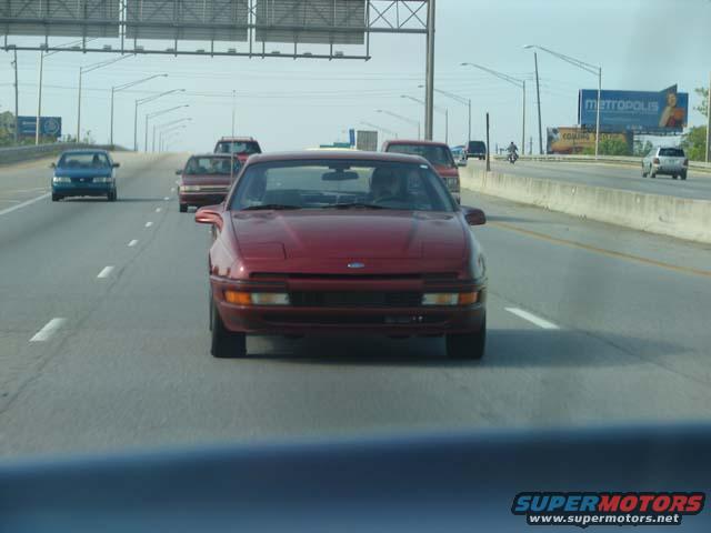 Red 1991 Ford Probe driving on a highway with other cars around