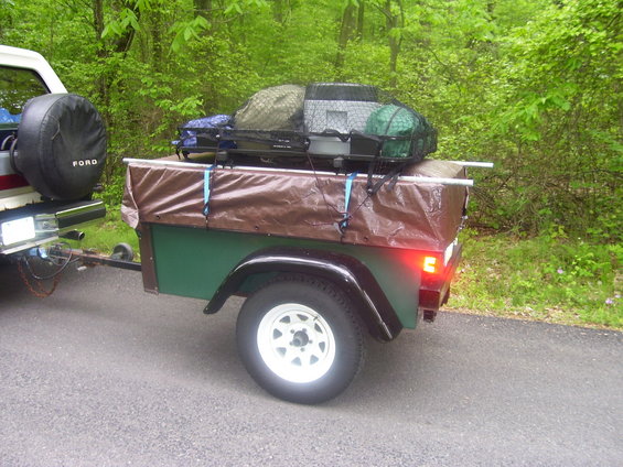 Trailer with camping gear and a spare tire labeled "FORD" on the back of a vehicle