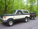 1991 Ford Bronco - Two-tone 1991 Ford Bronco is seen from the side, towing a trailer packed with luggage.