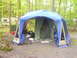 1991 Ford Bronco - A campsite scene features a large multi-room tent set up, with an RV visible in the wooded background.