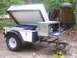 1991 Ford Bronco - A white Trailblazer camper trailer is set up in a wooded area with camping gear visible.