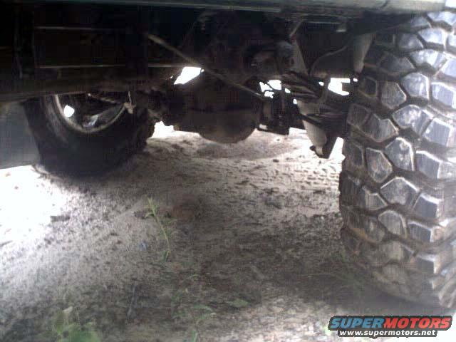 Undercarriage of a vehicle with a large off-road tire and suspension components visible