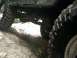 1996 Ford Bronco - The underside and aggressive tires of an off-road vehicle are visible as it navigates a rocky path.