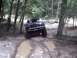 1996 Ford Bronco - This SUV navigates a challenging muddy path in a wooded area.