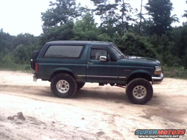 1996 Ford Bronco parked on a dirt road with trees in the background
