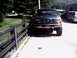 1996 Ford Bronco - A green Ford F-Series truck is parked in front of a building, with a wooden fence to its left.