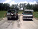 1996 Ford Bronco - Two 1996 Ford Broncos are seen from the rear, driving on a dirt road. The Bronco on the left has a spare tire mounted on the tailgate.