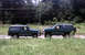 1996 Ford Bronco - Two dark green Ford Broncos are parked next to each other on a grassy roadside.