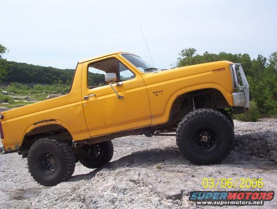 Yellow 1991 Ford Bronco with large tires on rocky terrain