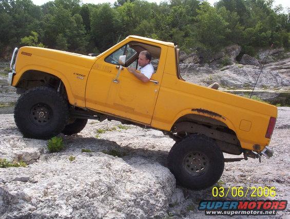 Yellow 1991 Ford Bronco climbing rocks