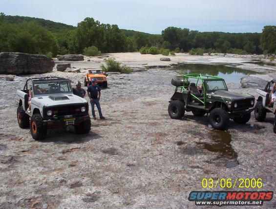 1991 Ford Bronco and other off-road vehicles on rocky ground near water