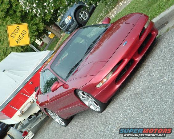 Red 1995 Ford Probe, front 3/4 view, parked next to a boat trailer. Blue SUV visible in background