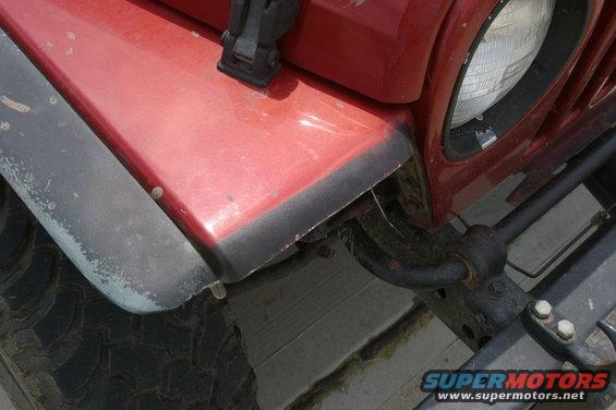 Red Jeep fender with black trim, showing part of the headlight and tire. The fender flares are worn