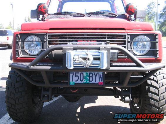 Red 1987 Suzuki Samurai with a winch and off-road bumper, front view