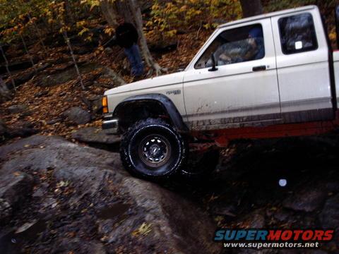 White Ford Ranger pickup truck navigating rocky terrain off-road
