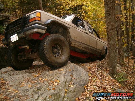 1990 Ford Ranger climbing over rocks on a wooded trail