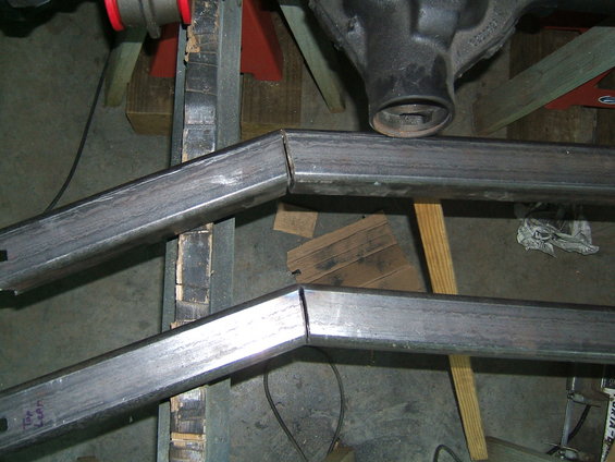 Metal frame pieces with angled cuts, supported by wood and metal stands