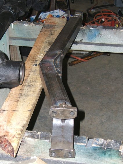 Metal bracket with two bolt holes on each end, resting on wooden planks