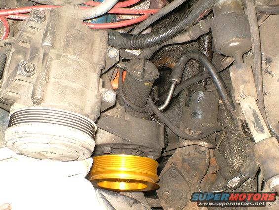 Engine bay view showing compressor, pulleys, hoses, and wiring