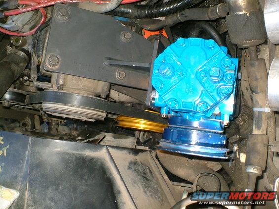 Blue compressor unit mounted with belts and pulleys in engine bay