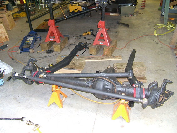 Front axle assembly on jack stands in a garage with tools around