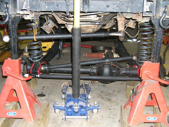 Vehicle undercarriage supported by jack stands, showing suspension and differential