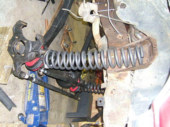 Front suspension part with coil springs and red bushings, on a blue jack