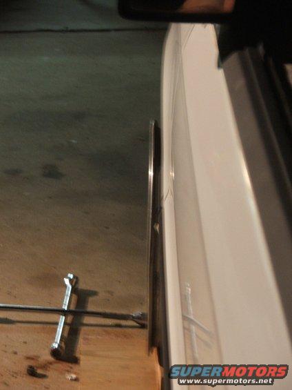 Side view of a white car's wheel and tire with a lug wrench on the floor