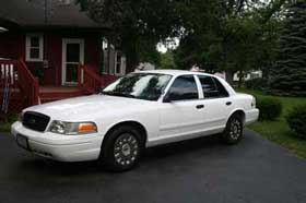 White 2003 Ford Crown Victoria sedan parked on asphalt driveway, front-left quarter view