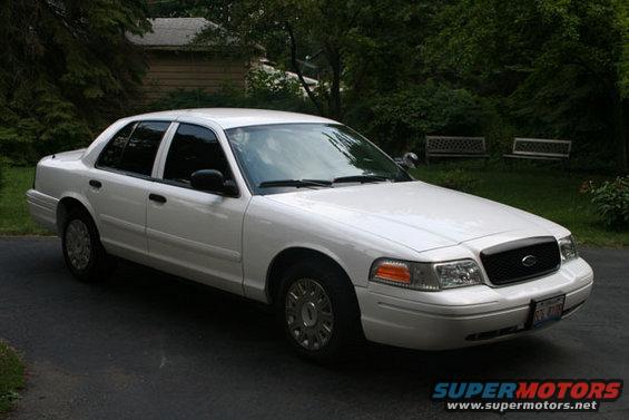 White 2003 Ford Crown Victoria, 3q front view. Grille and headlights are characteristic of this model year
