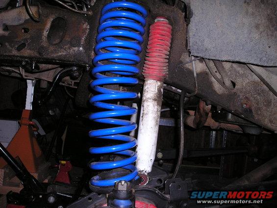 Blue coil spring and white shock absorber with red boot, part of vehicle suspension