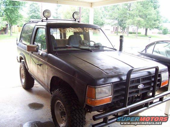 Black Ford Bronco II with roof lights and a brush guard parked under a carport. Text on windshield reads 'Dirty South OffRoad'