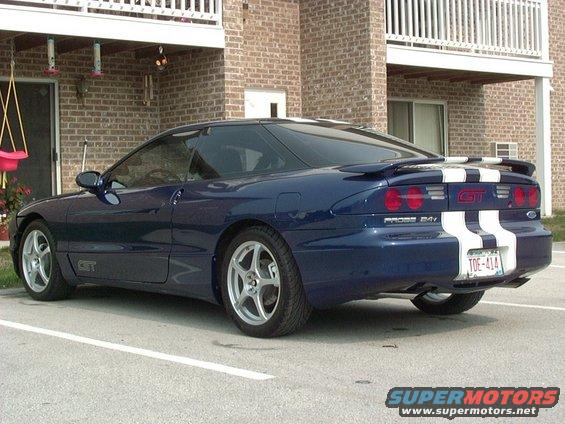 blue 1995 Ford Probe GT with white racing stripes parked in front of a brick building