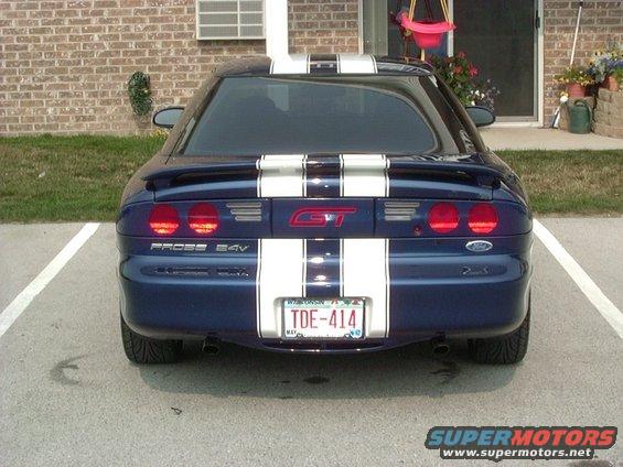 Blue 1995 Ford Probe GT with white racing stripes parked in a lot, rear view